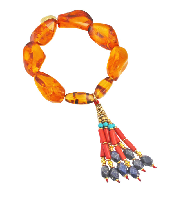 This authentic bohemian style amber tassel stretch bracelet is expertly crafted with genuine Nepalese amber and a unique, beaded tassel. The coral, lapis & turquoise beaded tassel design adds a free-spirited statement, while the authentic amber stones keep you grounded and confident.